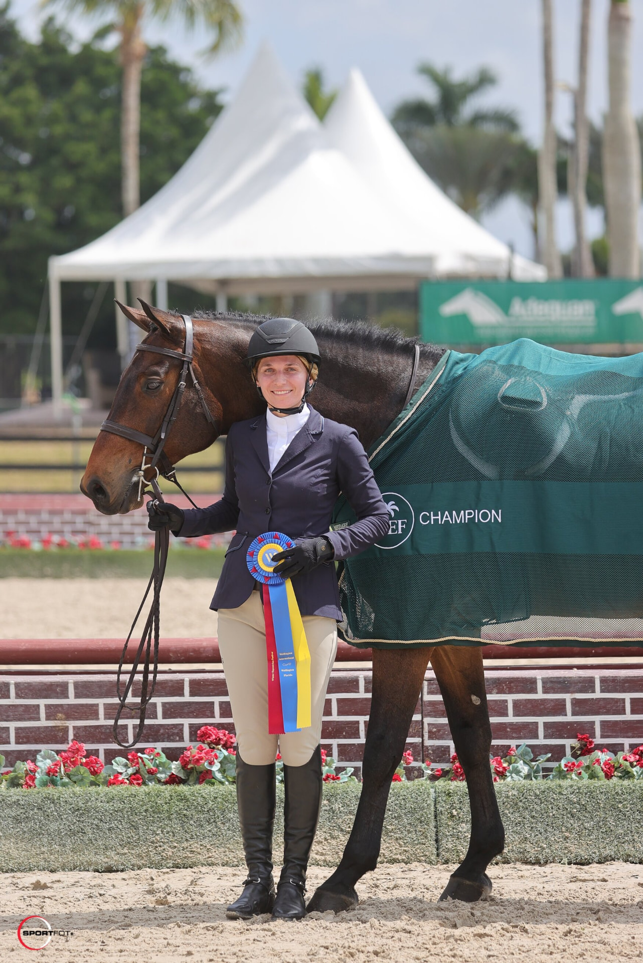 Rider with a champion ribbon beside her horse in a champion cooler at Lexington