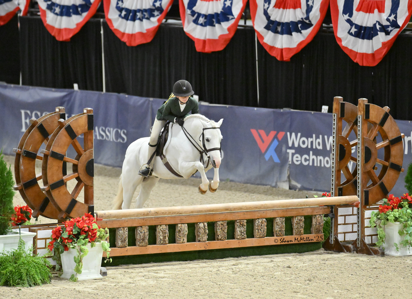 Rider and pony jumping an indoor hunter course